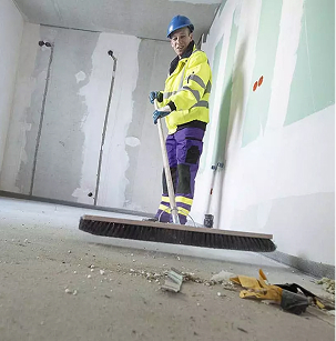 Mensch in Arbeitskleidung kehrt Abfall zusammen