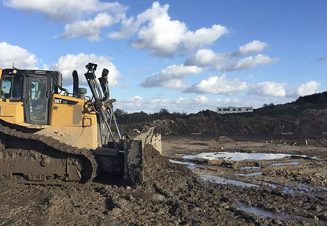 Radlader bewegt Erde in einem Steinbruch bei sonnigem Wetter.