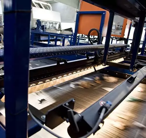 Maschinenanlage zur Holzverarbeitung mit Förderband und präziser Technik.