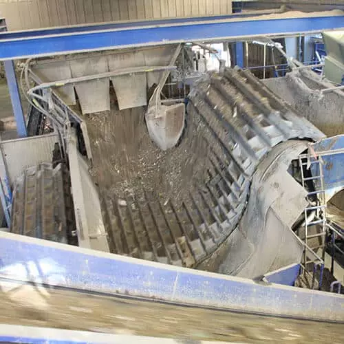 Blick auf eine moderne Recyclinganlage mit Förderband und Abfalltrennungssystem.