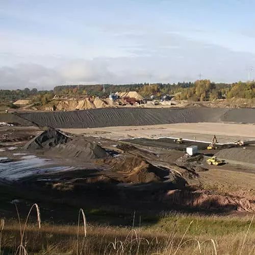 Baugelände mit Maschinen und Materialien für Erdarbeiten unter klarem Himmel.