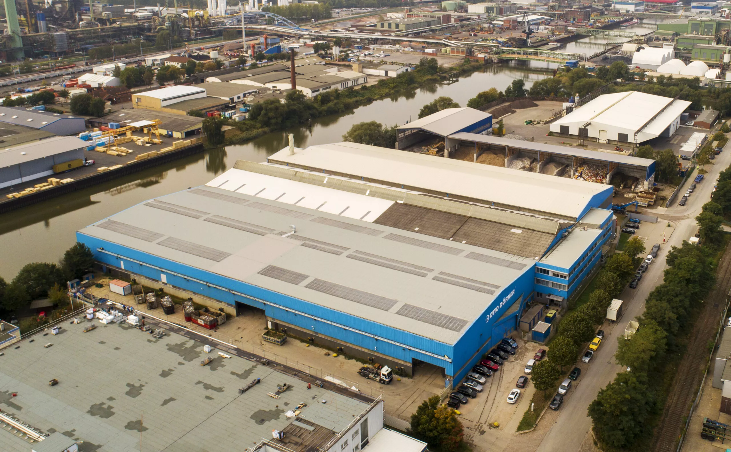 Luftaufnahme eines blauen Lagerhauses umgeben von Hochwasser in städtischem Gebiet.