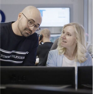 Zwei Mitarbeiter im Büro diskutieren am Computerbildschirm über ein Projekt.