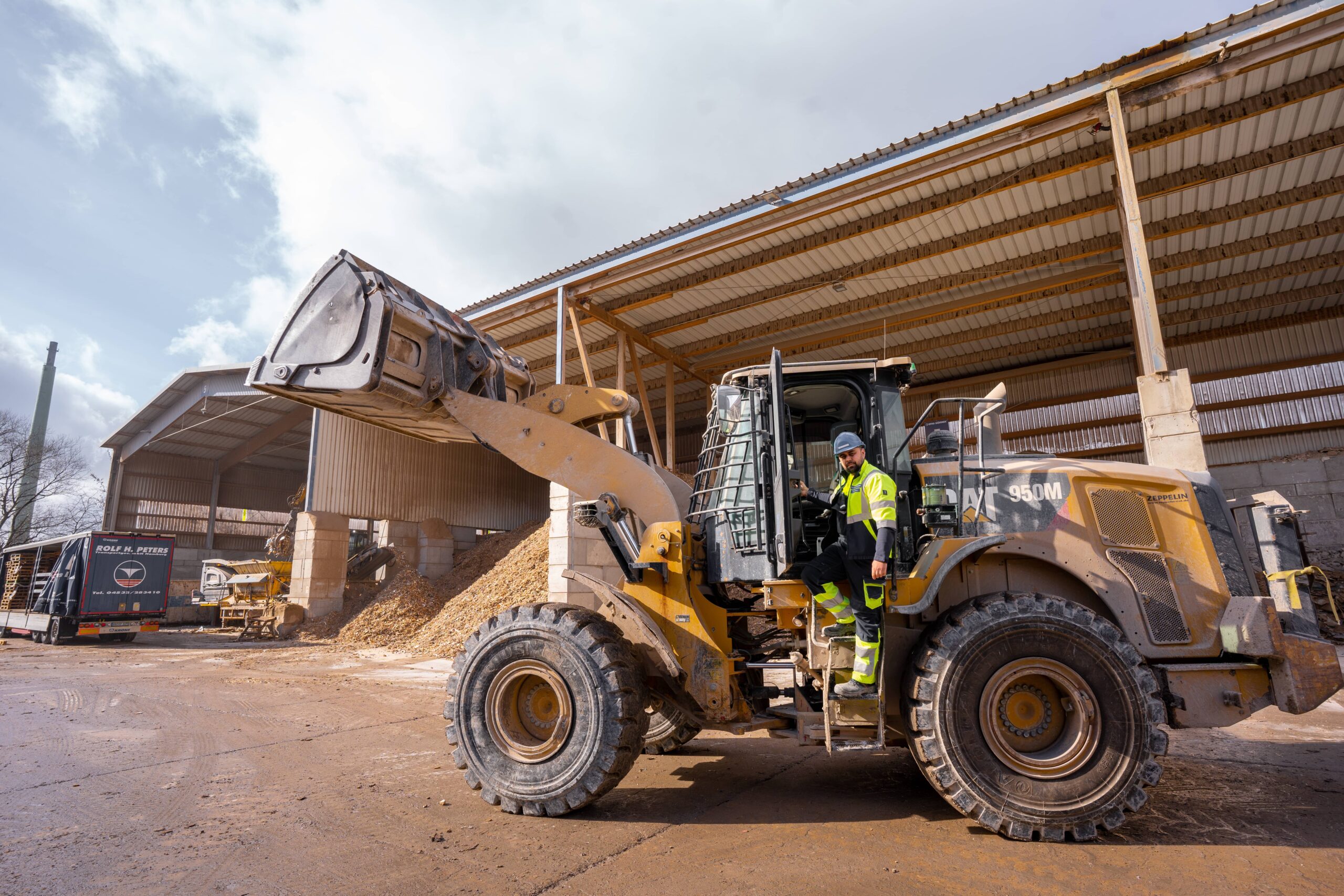 Bagger im Einsatz auf Baustelle, Arbeiter in Sicherheitskleidung, Materialladung.