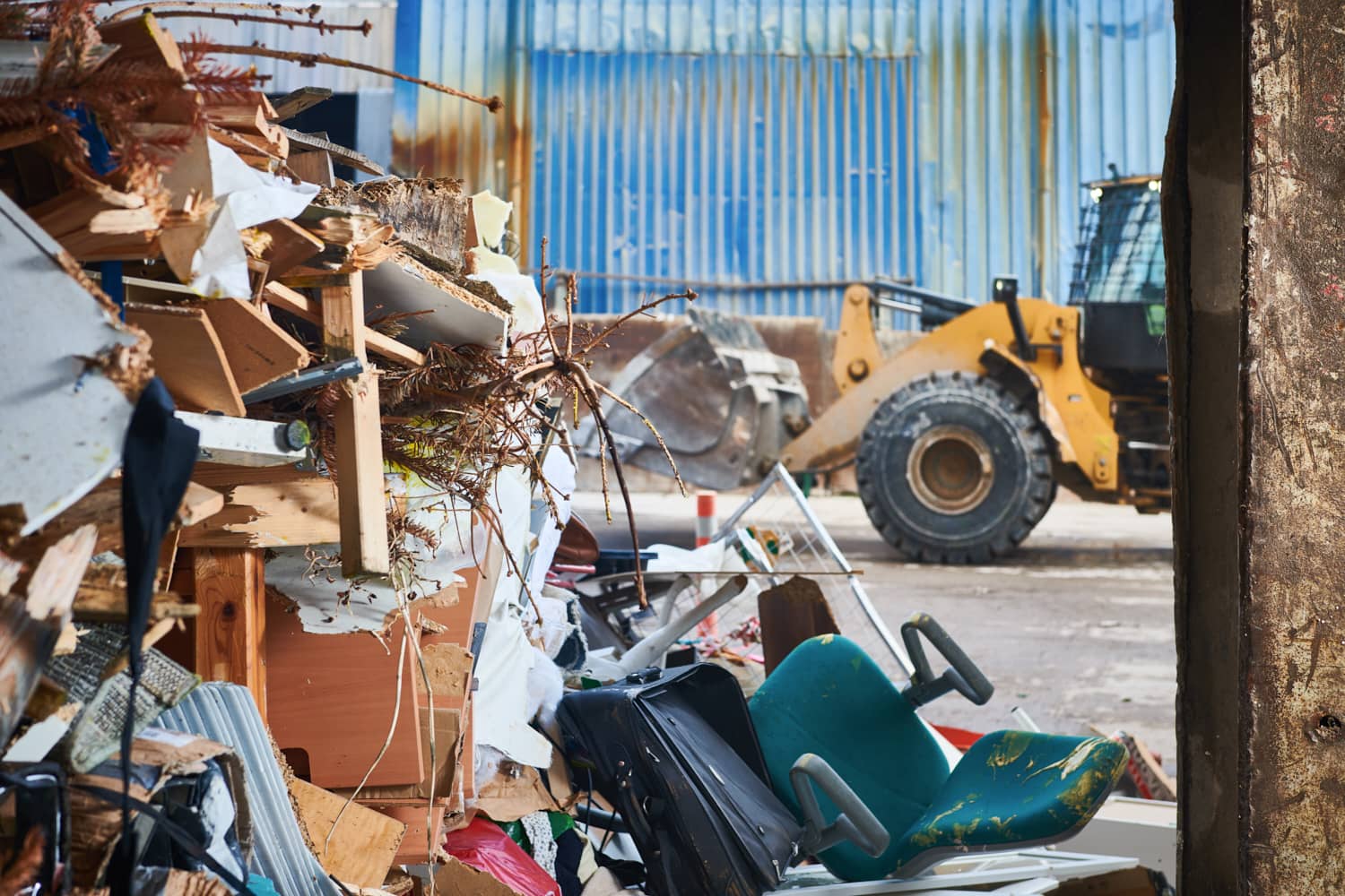 Baustellenabfall und Bauschutt mit Radlader auf einem Recyclingplatz in urbaner Umgebung.