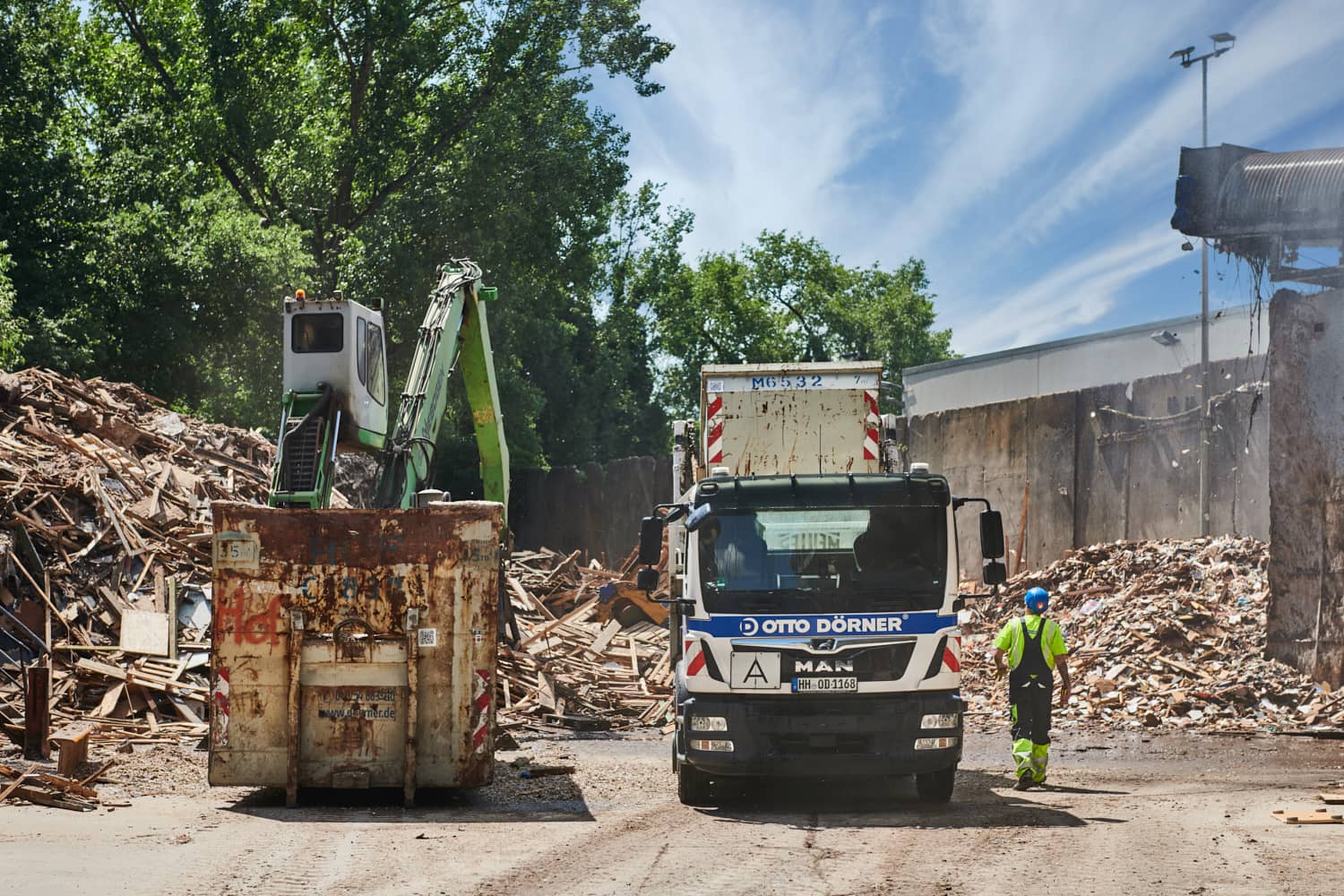 Bauabbruch mit Lkw und Container auf einer Baustelle unter blauem Himmel.