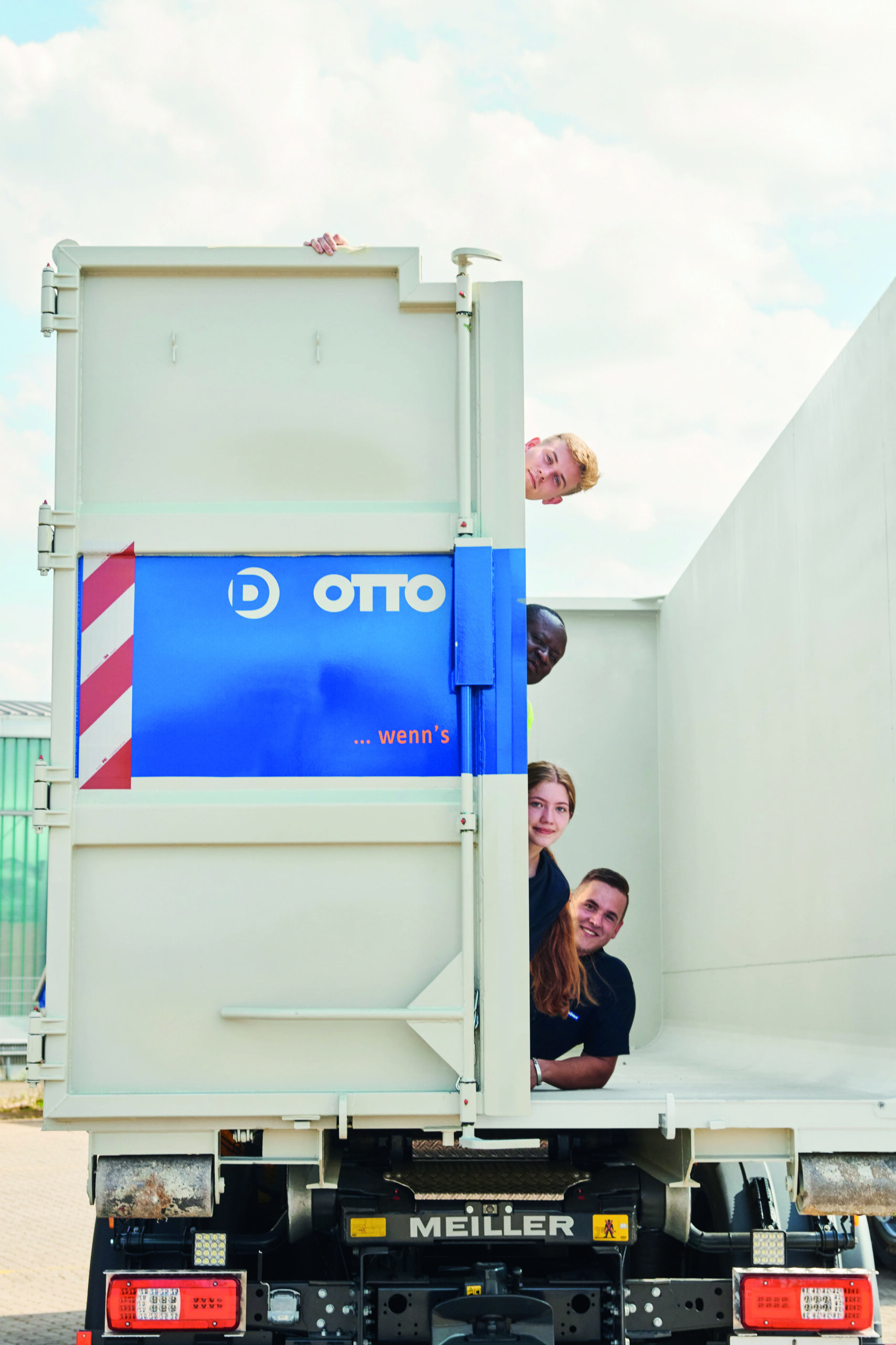Vier Personen schauen neugierig aus einem Container mit dem Logo von OTTO.