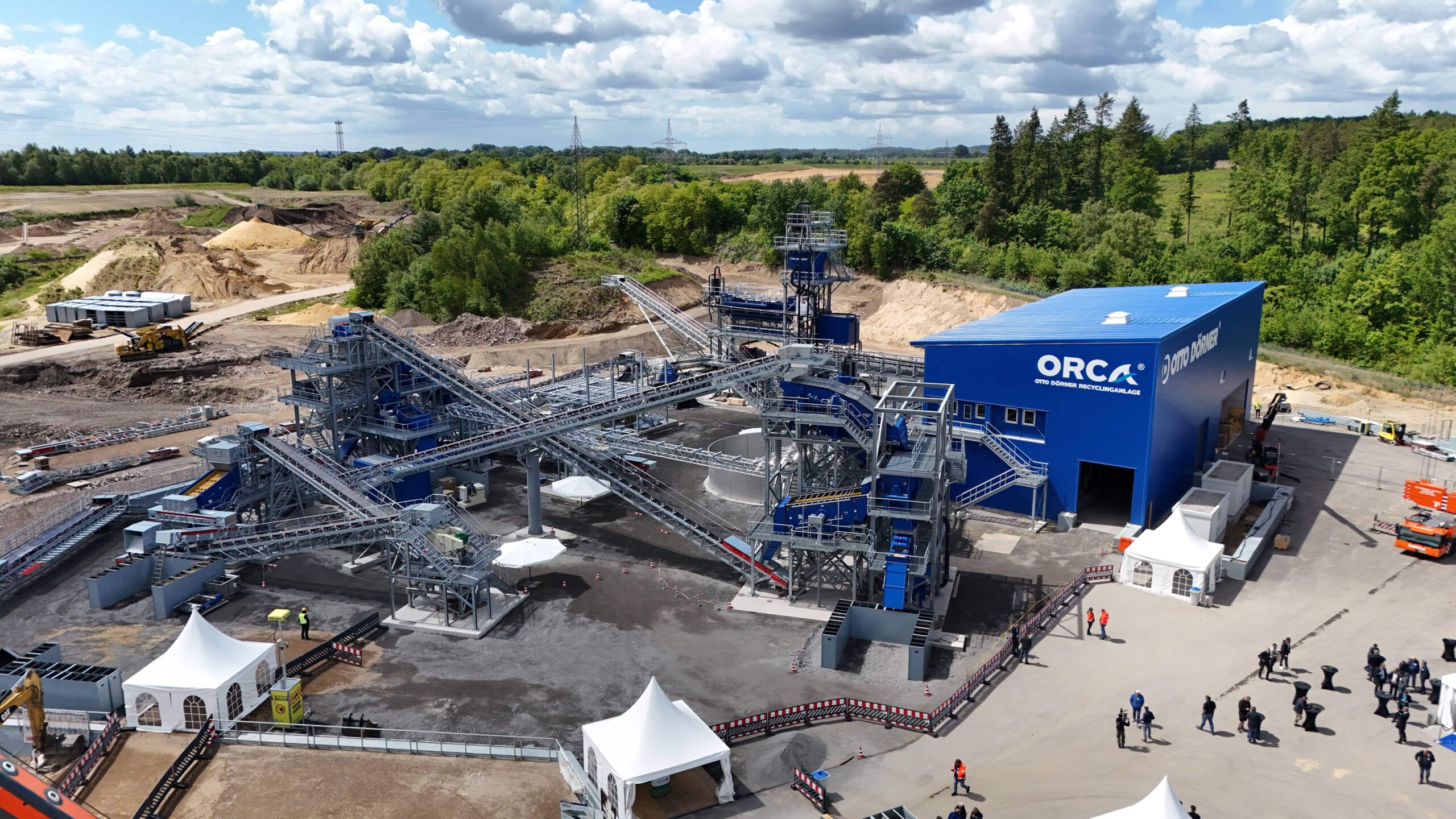 Moderne Recyclinganlage mit blauer Struktur und F&ouml;rderb&auml;ndern in einer nat&uuml;rlichen Umgebung.