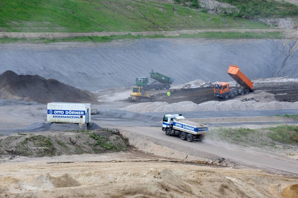 Bauarbeiten mit Lkw und Maschinen auf einer Baustelle in der Natur.