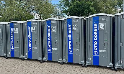 Mehrere mobile Toiletten von Otto Dörner in einer Reihe auf einem Parkplatz.