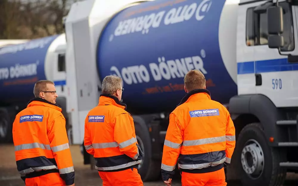 Arbeiter in orangefarbener Arbeitskleidung vor einem Betonmischwagen von Otto D&ouml;rner.