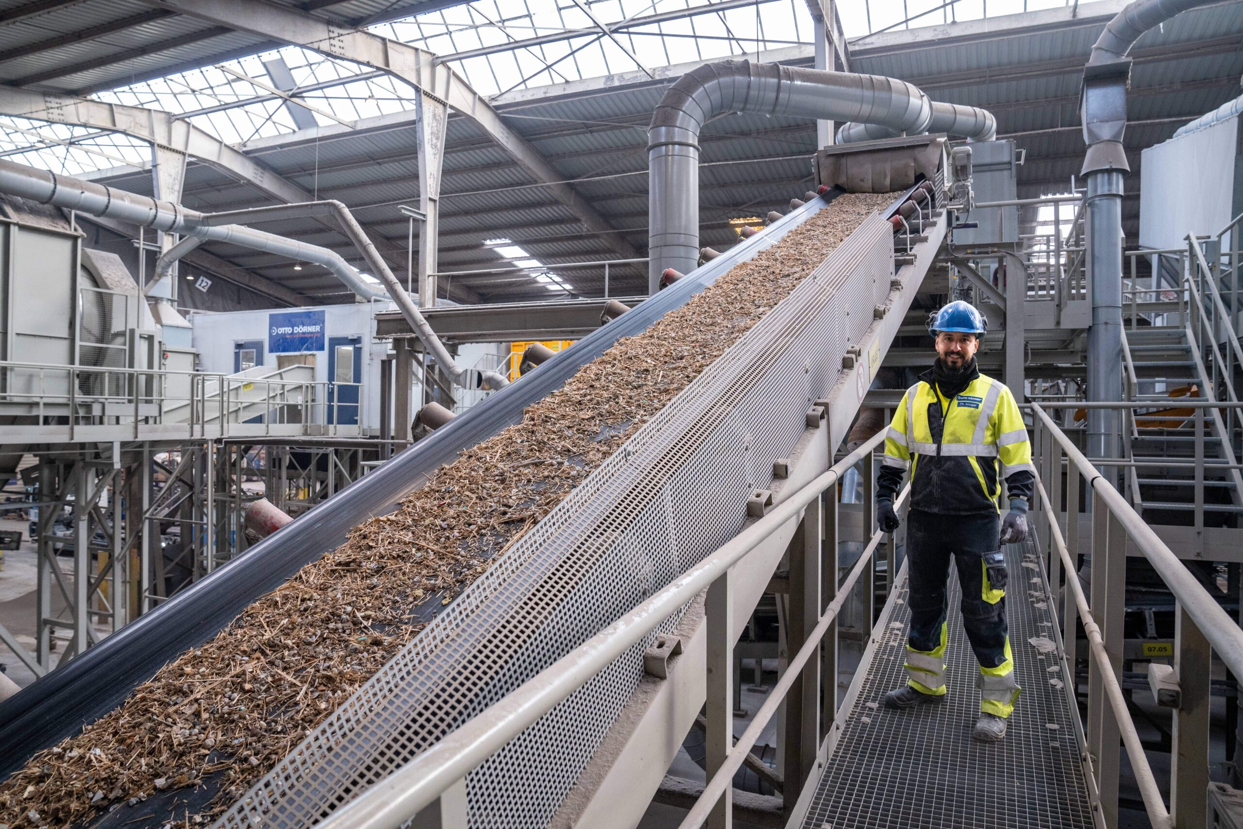 Mitarbeiter an F&ouml;rderband in einer modernen Produktionsanlage f&uuml;r Materialien.